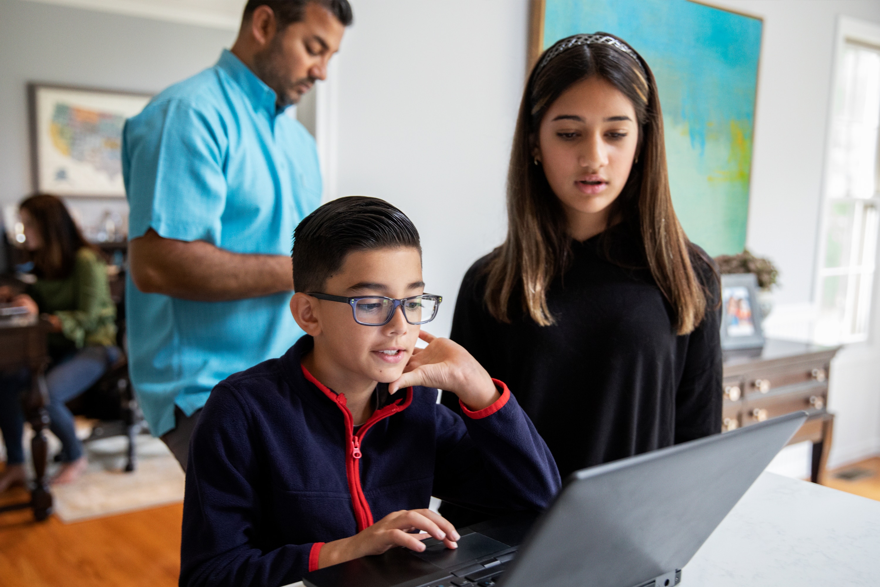 Two young children looking at a laptop with their father