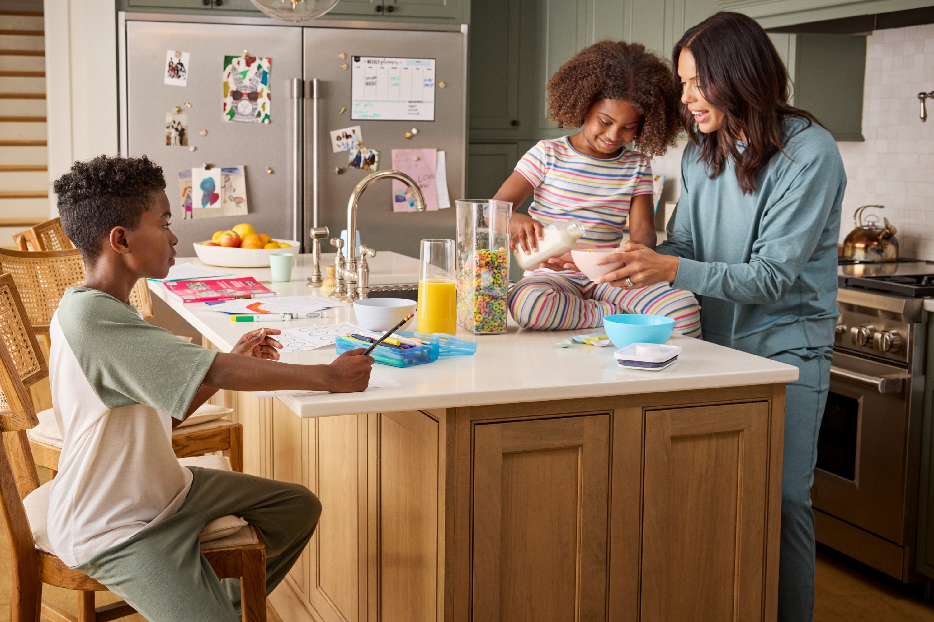 Two young children making breakfast with their mother in the kitchen